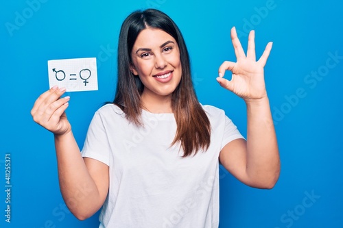 Beautiful woman asking for sex discrimination holding paper with gender equality concept doing ok sign with fingers, smiling friendly gesturing excellent symbol © Krakenimages.com