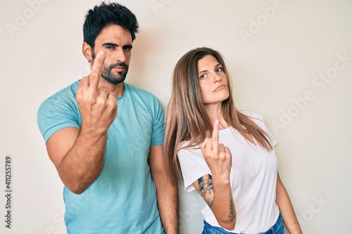 Beautiful young couple of boyfriend and girlfriend together showing middle finger, impolite and rude fuck off expression
