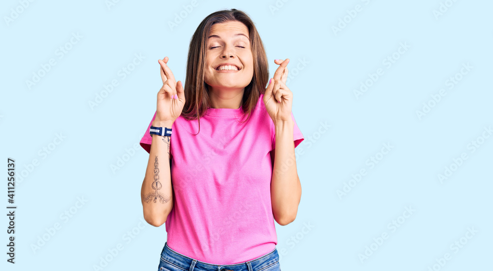 Beautiful caucasian woman wearing casual clothes gesturing finger crossed smiling with hope and eyes closed. luck and superstitious concept. Beautiful caucasian woman wearing casual clothes gesturing finger crossed smiling with hope and eyes closed. luck and superstitious concept.