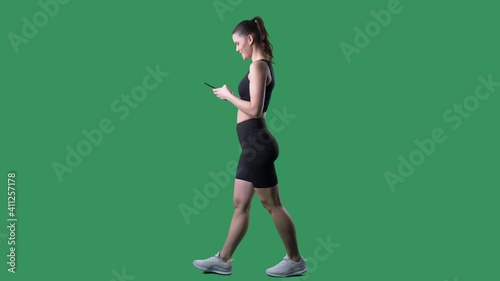 Side view of happy fit young woman using smart phone app. Full body on chroma key green screen.