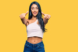 Beautiful hispanic woman wearing casual clothes approving doing positive gesture with hand, thumbs up smiling and happy for success. winner gesture.
