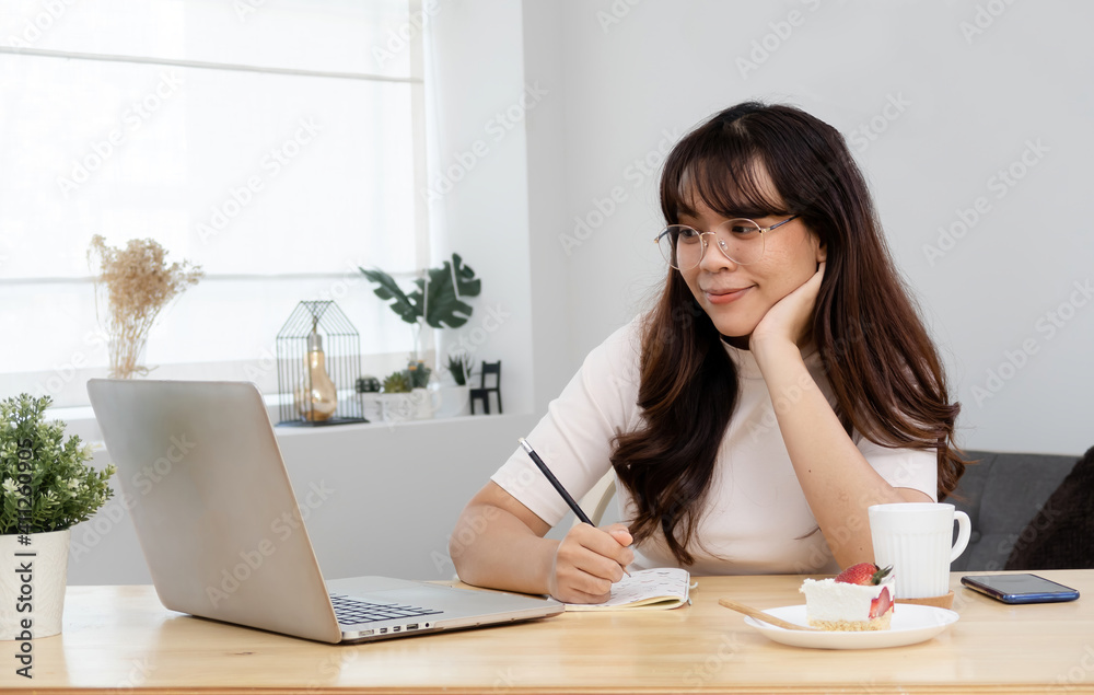 Concept working at home Asian woman sitting and looking at screen. Ready to write on paper with intention Is a new normal life of work Concept working at home Asian woman sitting and looking at screen. Ready to write on paper with intention Is a new normal life of work