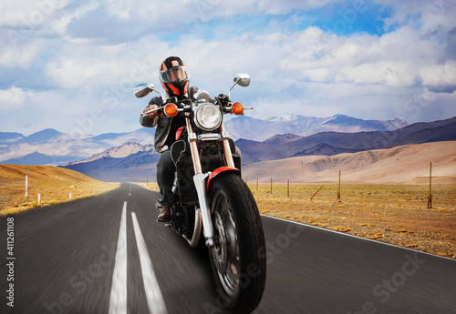 Fototapeta Naklejka Na Ścianę i Meble -  a biker on a motorcycle rides on an asphalt road in the mountains