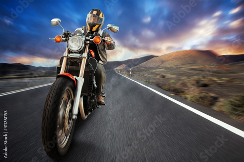 a biker on a motorcycle rides on an asphalt road in the mountains