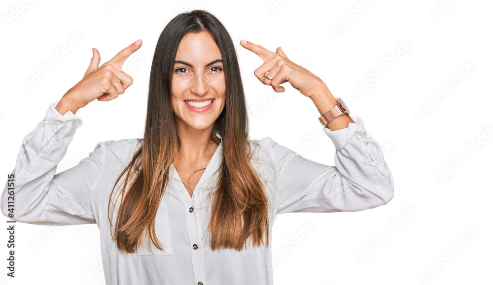 Young beautiful woman wearing casual clothes smiling pointing to head with both hands finger, great idea or thought, good memory Young beautiful woman wearing casual clothes smiling pointing to head with both hands finger, great idea or thought, good memory