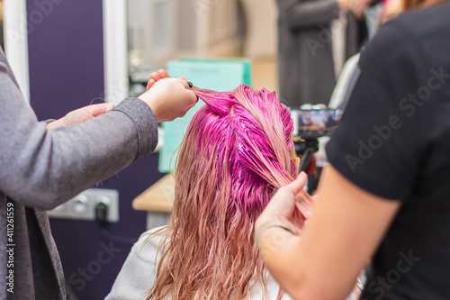 Hair dyeing for a girl in a beauty salon, long hair pink.
