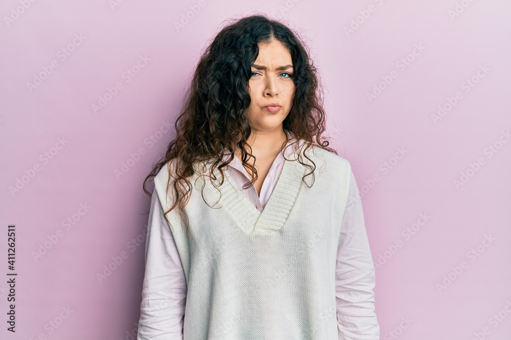 Young brunette woman with curly hair wearing casual clothes skeptic and nervous, frowning upset because of problem. negative person. Young brunette woman with curly hair wearing casual clothes skeptic and nervous, frowning upset because of problem. negative person.