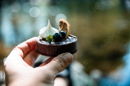 Mini tart tartalette in hand with meringue blueberry and orange photo