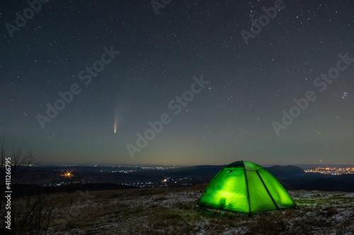 Winter tent in the mountains against the background of stars and comets © onyx124
