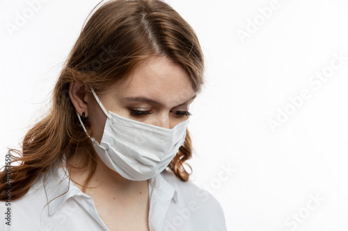 Fotografía Sad young woman in a medical mask tilted her head down