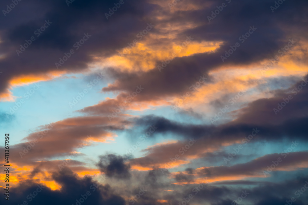 Dramatic heaven: sunlit dark clouds in blue sky at sunset