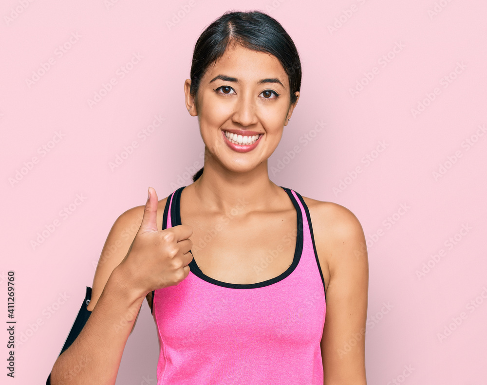 Beautiful asian young sport woman wearing sportswear and arm band doing happy thumbs up gesture with hand. approving expression looking at the camera showing success. Beautiful asian young sport woman wearing sportswear and arm band doing happy thumbs up gesture with hand. approving expression looking at the camera showing success.