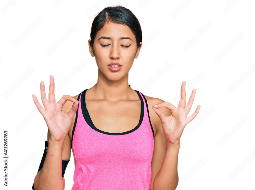 Beautiful asian young sport woman wearing sportswear and arm band relax and smiling with eyes closed doing meditation gesture with fingers. yoga concept. Beautiful asian young sport woman wearing sportswear and arm band relax and smiling with eyes closed doing meditation gesture with fingers. yoga concept.