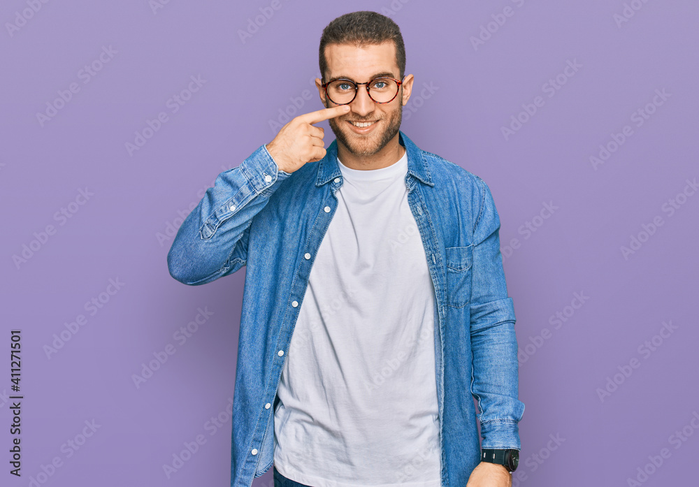 Young caucasian man wearing casual clothes pointing with hand finger to face and nose, smiling cheerful. beauty concept Young caucasian man wearing casual clothes pointing with hand finger to face and nose, smiling cheerful. beauty concept