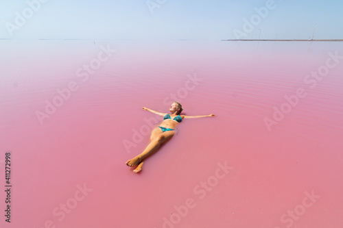 Woman swimming in salt plains waters colored with pink algae.