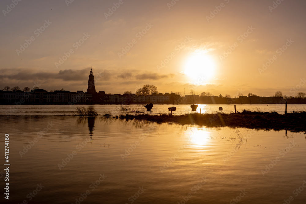 Low sun over the floodplains overflown by high water level of the river IJssel passing by Hanseatic city of Zutphen, The Netherlands, with cityscape in the background