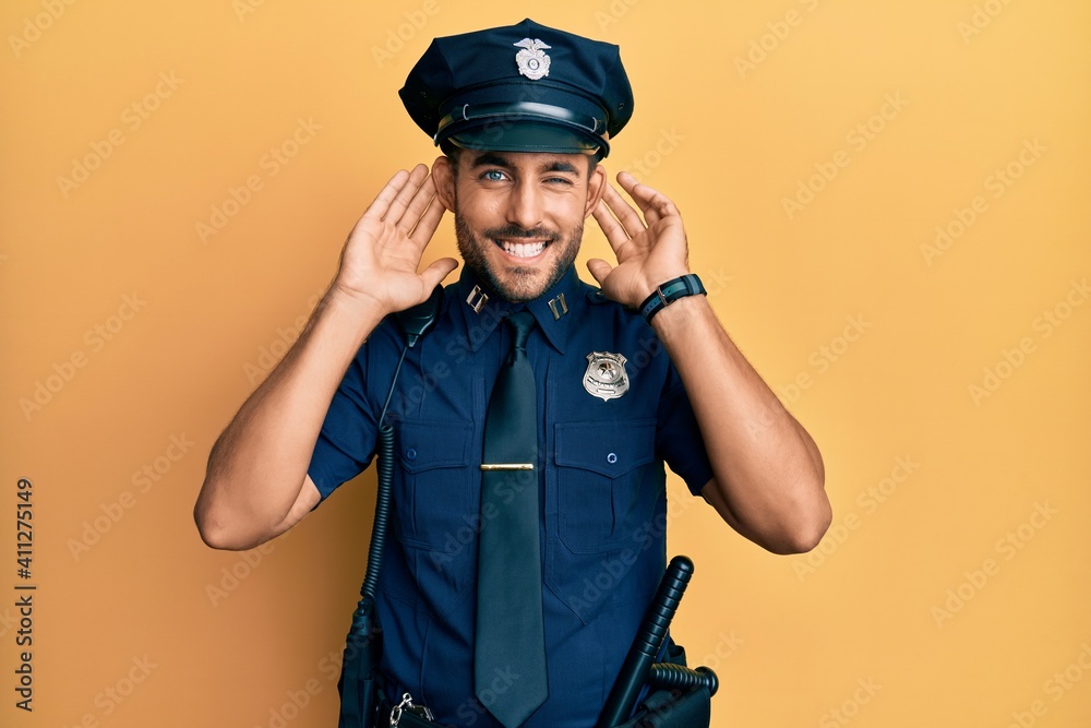 Handsome hispanic man wearing police uniform trying to hear both hands on ear gesture, curious for gossip. hearing problem, deaf Handsome hispanic man wearing police uniform trying to hear both hands on ear gesture, curious for gossip. hearing problem, deaf