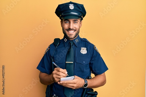 Fotografia Handsome hispanic man wearing police uniform writing traffic fine smiling with a happy and cool smile on face