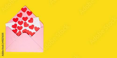 Valentine's Day card. Paper hearts fly out of pink paper envelope on yellow background. Paper art on valentine day. craft style. Space for text. concept of Valentine's Day. Long wide banner © mars58