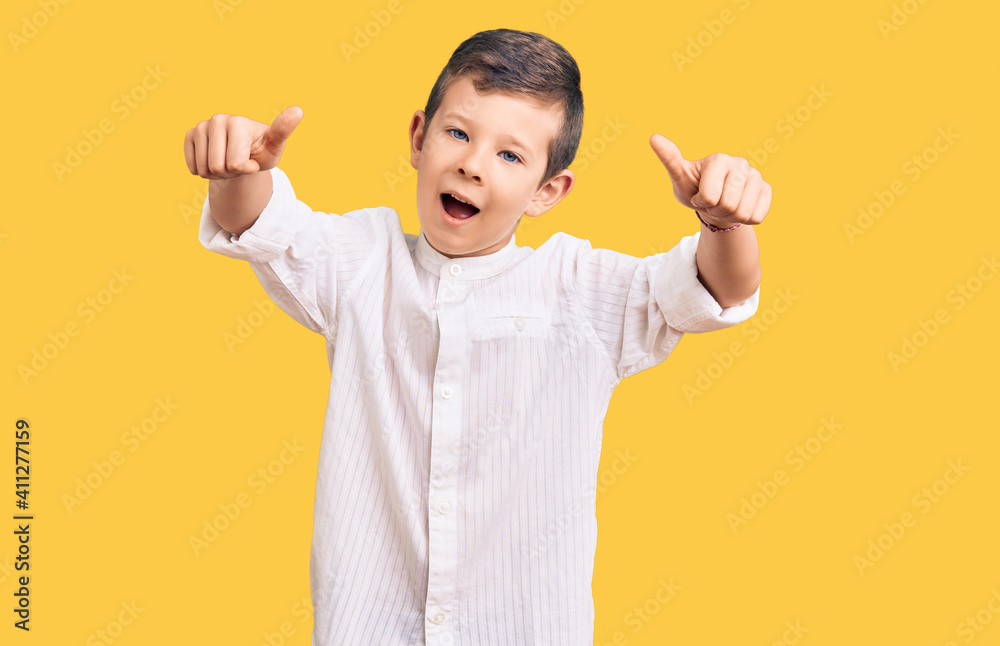 Cute blond kid wearing elegant shirt approving doing positive gesture with hand, thumbs up smiling and happy for success. winner gesture. Cute blond kid wearing elegant shirt approving doing positive gesture with hand, thumbs up smiling and happy for success. winner gesture.