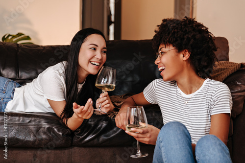 Snapshot of girls chatting, smiling and holding glasses of white wine photo