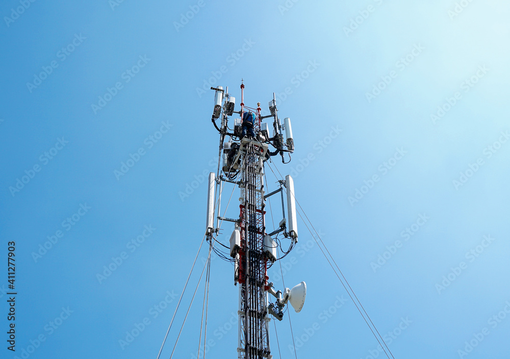 workers are working at 5g antenna tower for maintaining.serves cellular antenna, technician worker repair telecommunication tower on sunlight at background. workers are working at 5g antenna tower for maintaining.serves cellular antenna, technician worker repair telecommunication tower on sunlight at background.