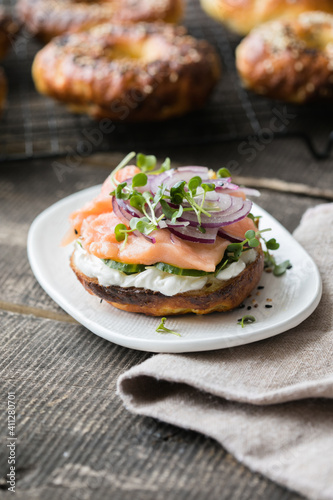 Smoked salmon bagels sandwich with soft cheese and micro greens on a cutting board.