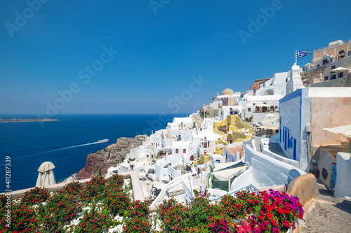 Beautiful view of Oia with traditional white houses and windmills in village, Santorini island, Greece