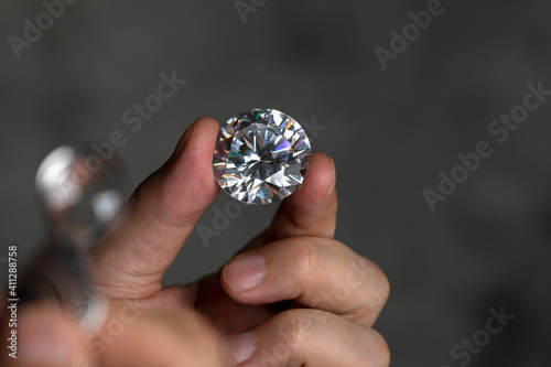 Large polished round cut diamond in hand close up front view. High quality photo photo