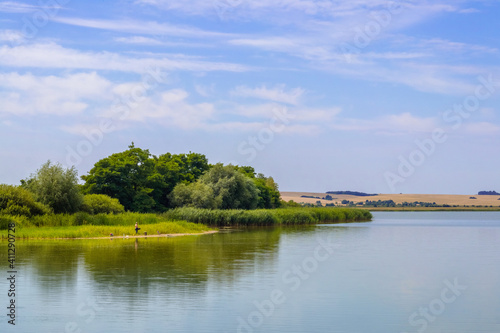 Summer landscape with river and trees reflected in water on a sunny day