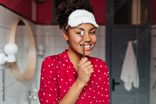 Cute brunette woman in red shirt is smiling and holding toothbrush