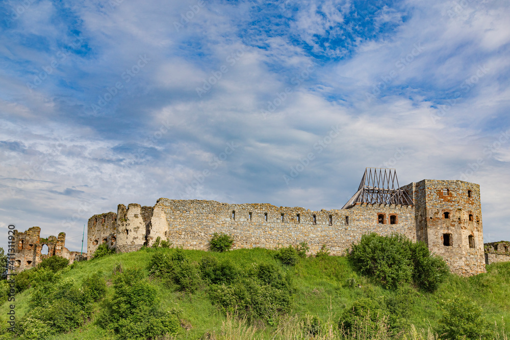 Ancient ruins of castle on green grass on hill. Ukrainian architectural  landmark.