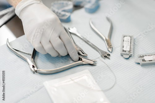 Orthodontist working with a model of teeth and taking instrument from the table. Orthodontic treatment at the laboratory. Close-up. High quality photo