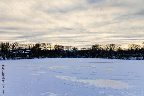 Landscape on a frozen river in a winter evening