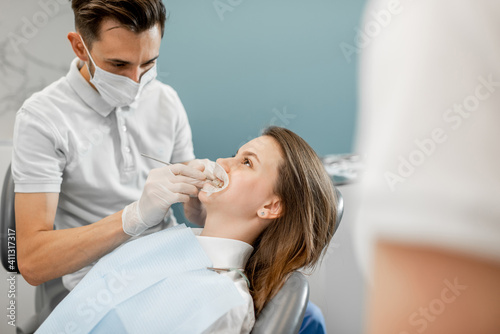 Young female patient with dental braces during a regular orthodontic visit. Dentist adjusting orthodontic brackets. High quality photo