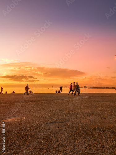 Thessaloniki Greece February 2, 2021:people are walking and enjoying a relaxed time by the sea during beautiful sunset with magical colors