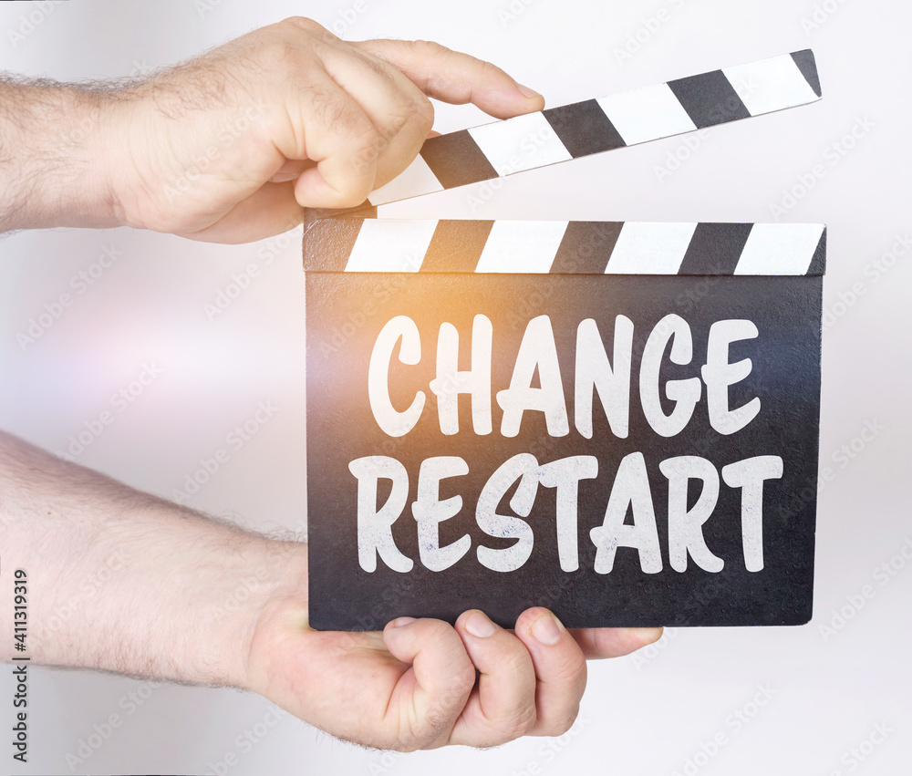 On a white background, a man holds a clapperboard in his hands on which it is written - CHANGE RESTART