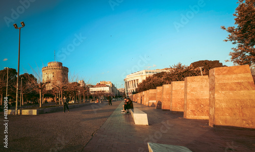 Thessaloniki Greece February 2, 2021:people are walking under the colors of the sunset around The white tower the symbol of the city