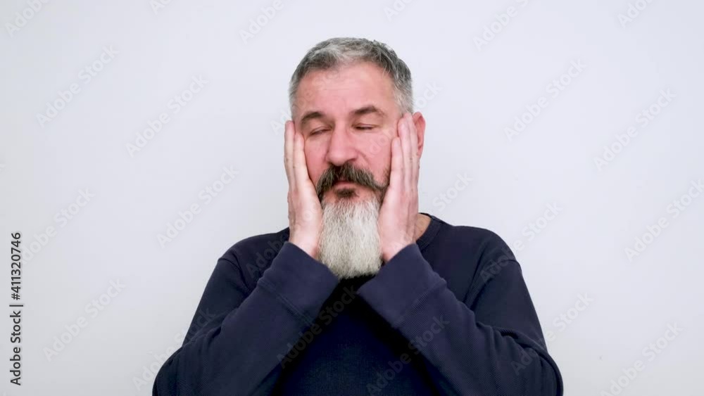 Upset mature bearded man grabs his head, hits his forehead, severe depression or headache, white background Upset mature bearded man grabs his head, hits his forehead, severe depression or headache, white background