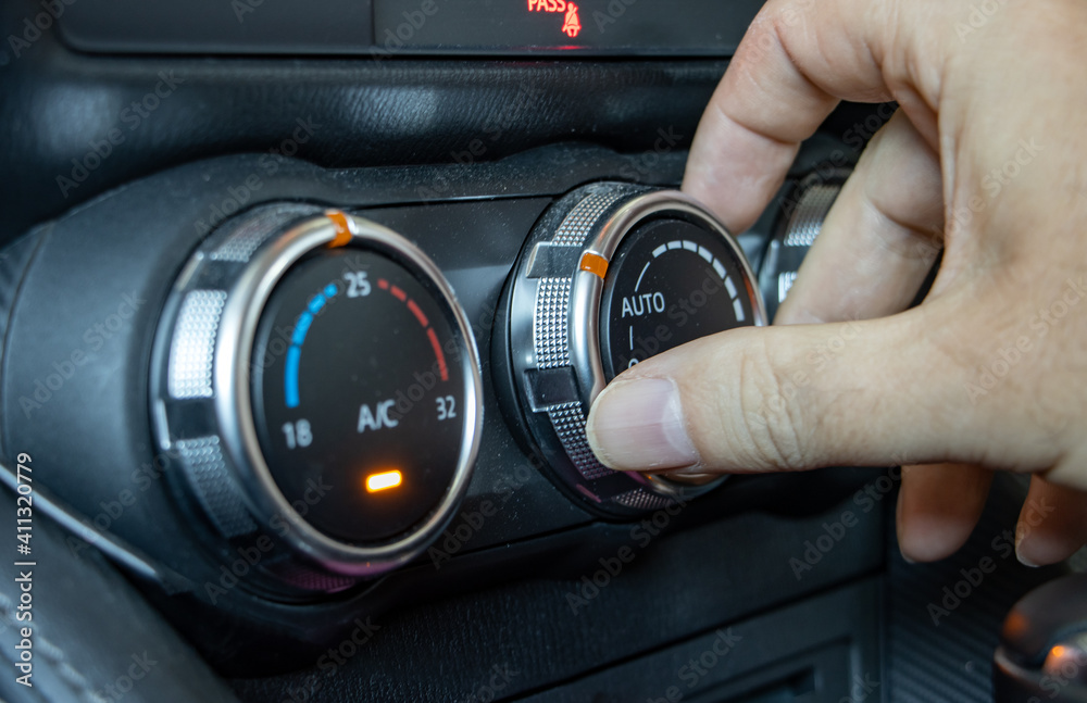 Using air condition in a car, close up. The hand manipulates the ventilation control knob inside the car.