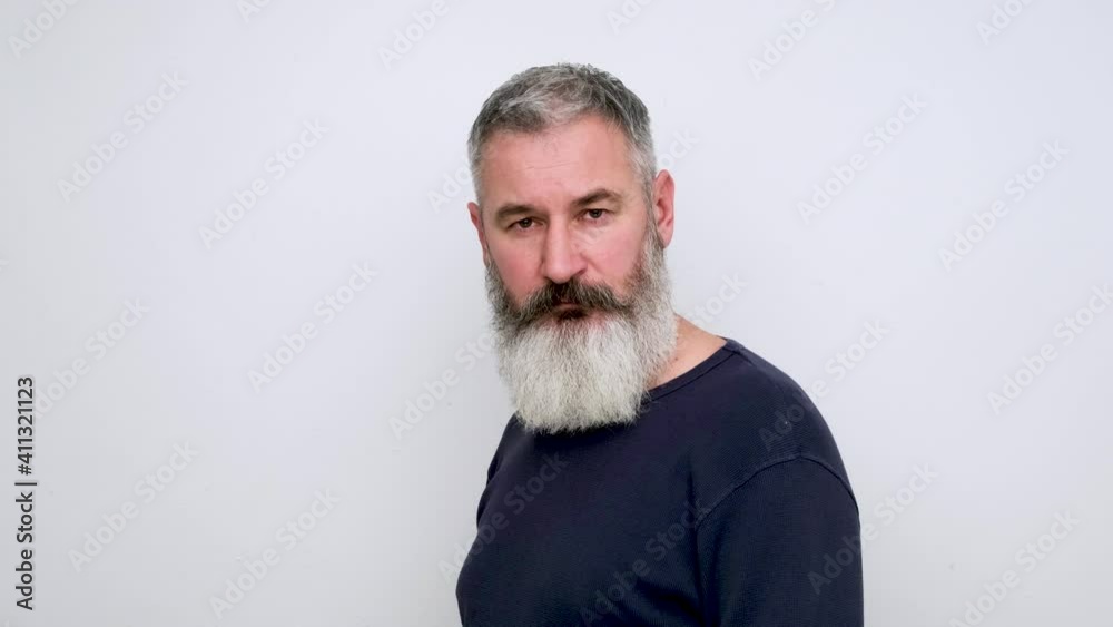 Mature bearded man comes out right, looks at camera and walks further, white background Mature bearded man comes out right, looks at camera and walks further, white background