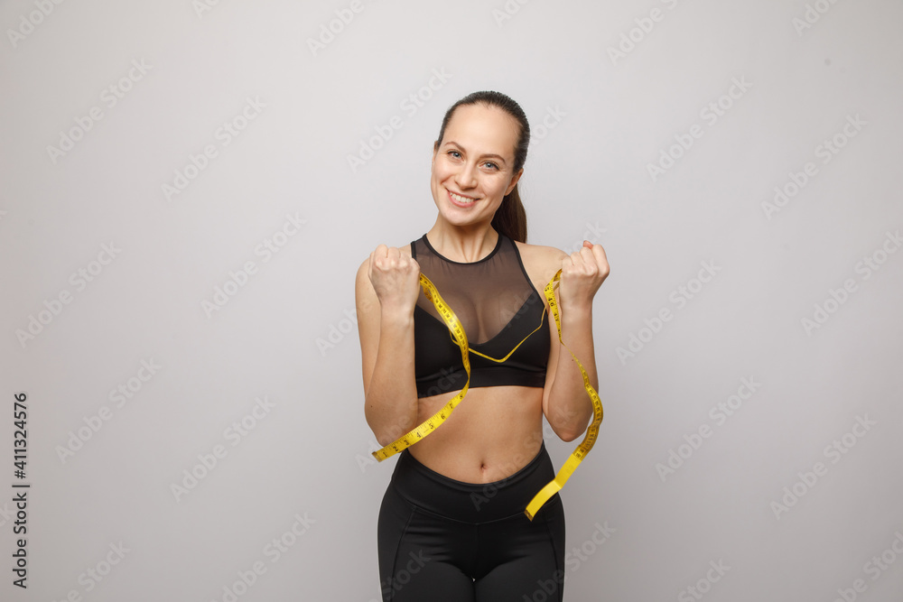 A healthy, fit girl measuring her waist after fitness exercise A healthy, fit girl measuring her waist after fitness exercise