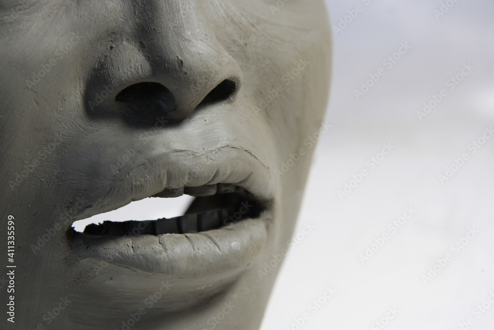 Sculpture in creation process. Details of female face, wet clay sculpture. Small nose, teeth and
