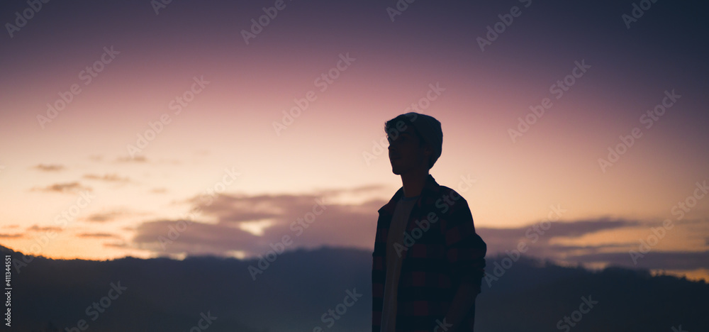 Young man alone  at dusk. Concept of individuality, loneliness, faith or transcendent.