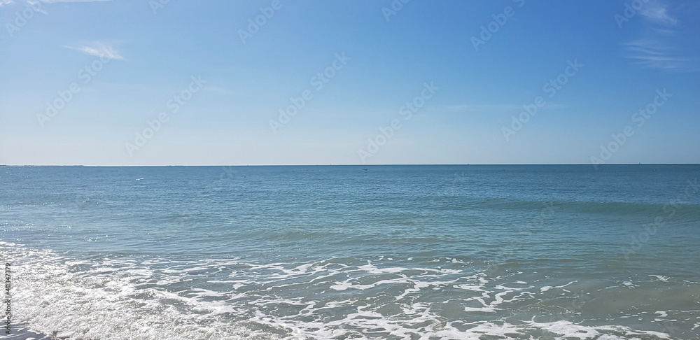 Beach angled to show waves, sea foam, and horizon taken from St. Pete Beach, Florida in the Winter.  Clear blue sky and crystal blue waters of the Gulf of Mexico stretch out to the horizon.