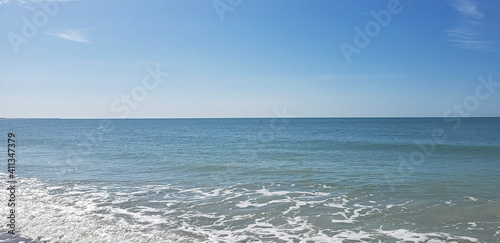 Beach angled to show waves  sea foam  and horizon taken from St. Pete Beach  Florida in the Winter.  Clear blue sky and crystal blue waters of the Gulf of Mexico stretch out to the horizon.