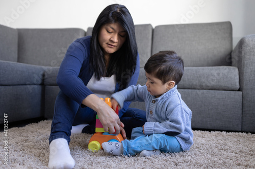 Mexican mother playin with her son on living room  