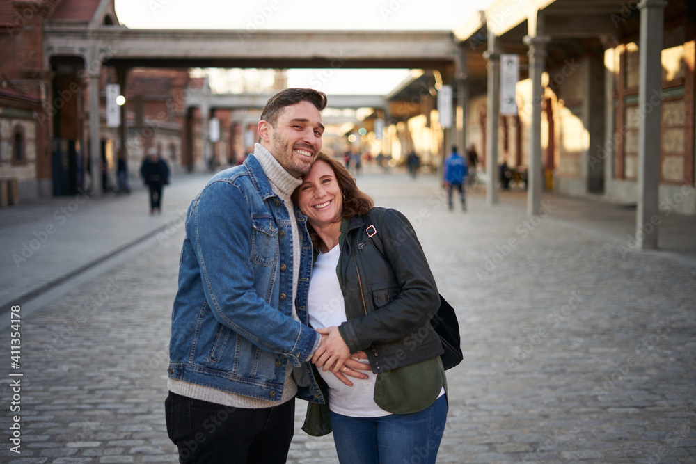 Young adult couple poses happily, pregnant woman. Portrait. Soft focus background. Couple holding hands. High quality photo