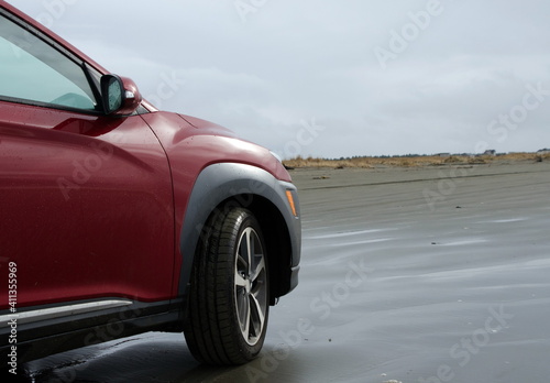 Red hatchback riding on sandy beach in Ocean Shores © Dmitri Kotchetov