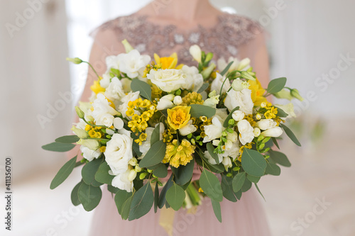 Elegant spring white and yellow wedding bouquet of daffodils, lisianthus, eucalyptus and matricaria camilla.